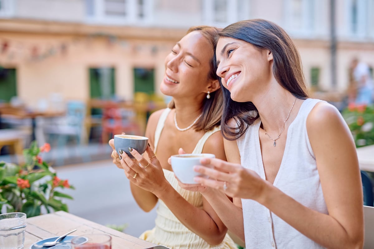 Friends laughing together at an outdoor cafe, representing everyday social life